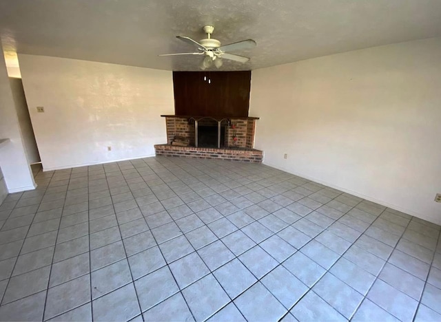 unfurnished living room featuring a brick fireplace, a textured ceiling, and ceiling fan