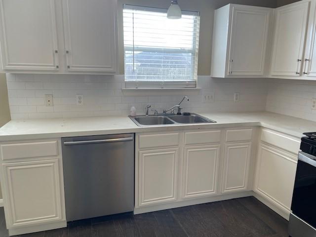 kitchen with pendant lighting, sink, dark wood-type flooring, white cabinetry, and stainless steel dishwasher