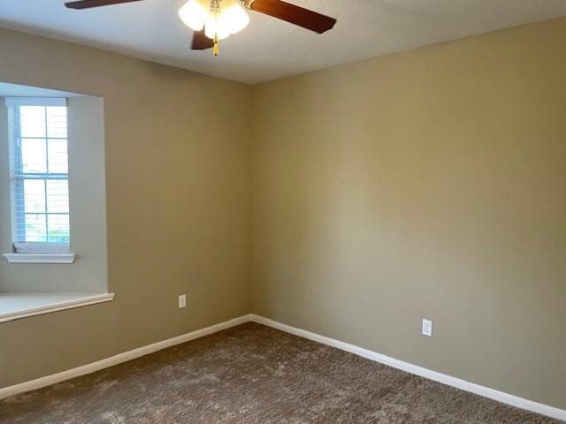 empty room featuring dark carpet and ceiling fan