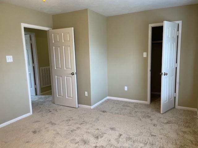 unfurnished bedroom with a spacious closet, light colored carpet, and a closet