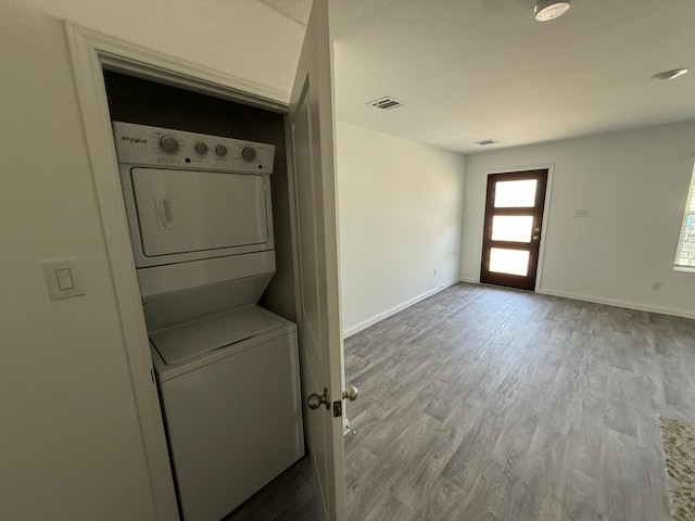 laundry room featuring stacked washer and clothes dryer and hardwood / wood-style floors