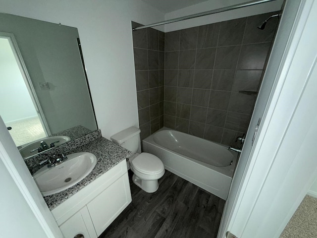 full bathroom with hardwood / wood-style flooring, vanity, tiled shower / bath, and toilet