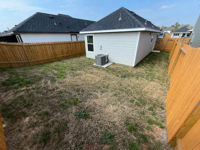 rear view of property featuring central AC and a lawn