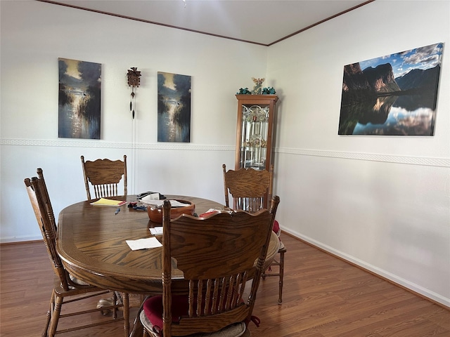 dining room with crown molding, baseboards, and wood finished floors