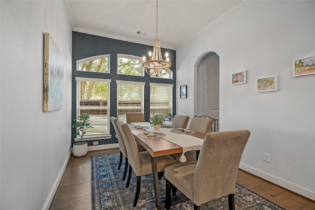 dining space featuring crown molding, dark wood-type flooring, and a chandelier