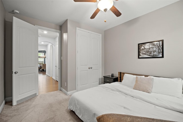 bedroom featuring ceiling fan, light carpet, and a closet