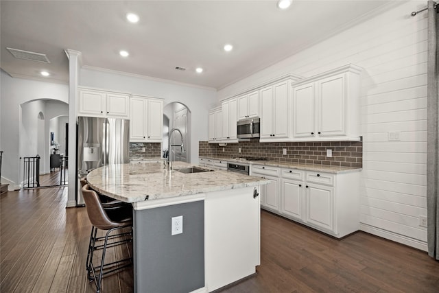 kitchen with stainless steel appliances, white cabinetry, a kitchen island with sink, and sink