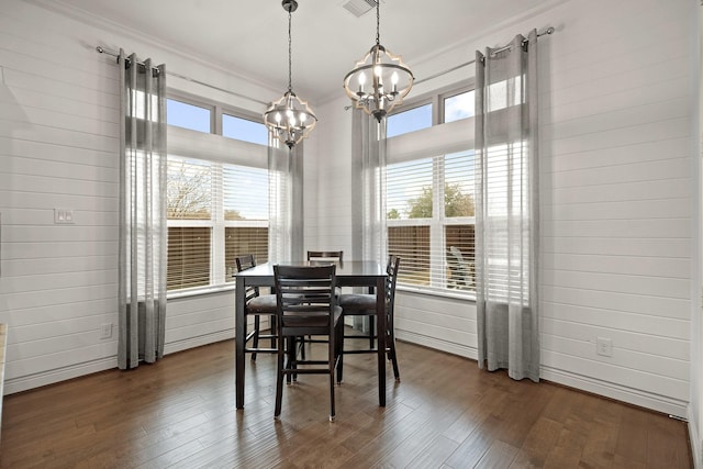 dining space with an inviting chandelier, dark hardwood / wood-style flooring, and wood walls