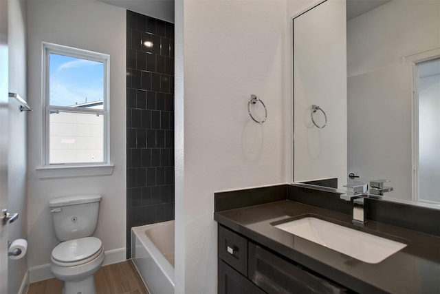 full bathroom featuring hardwood / wood-style flooring, vanity, tiled shower / bath, and toilet