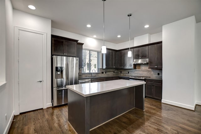 kitchen with stainless steel appliances, dark brown cabinetry, a kitchen island, dark hardwood / wood-style flooring, and decorative light fixtures