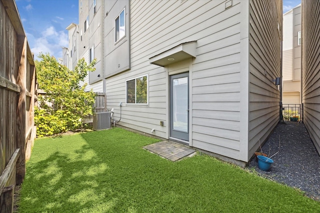 rear view of house with central AC unit and a lawn