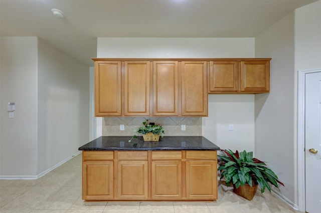 kitchen with dark stone countertops, light tile patterned floors, and decorative backsplash