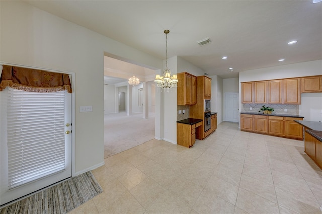 kitchen with tasteful backsplash, appliances with stainless steel finishes, decorative light fixtures, and an inviting chandelier