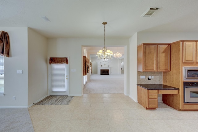 kitchen featuring an inviting chandelier, stainless steel appliances, tasteful backsplash, light carpet, and decorative light fixtures