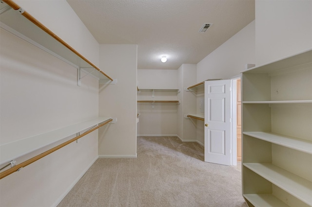 walk in closet featuring light colored carpet