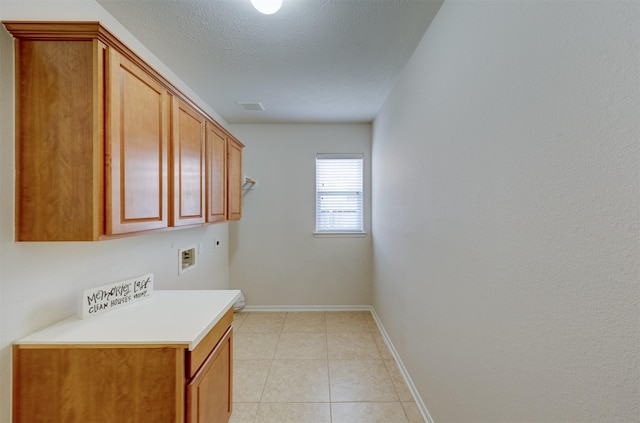 laundry room featuring cabinets, light tile patterned floors, hookup for a washing machine, hookup for an electric dryer, and a textured ceiling