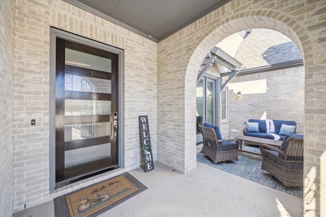 view of exterior entry featuring outdoor lounge area and brick siding