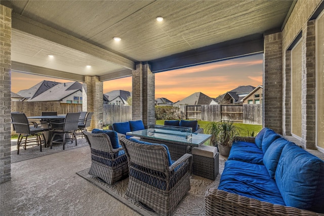 patio terrace at dusk featuring an outdoor hangout area, outdoor dining area, a fenced backyard, and a residential view