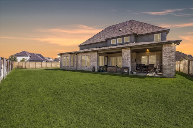 rear view of property featuring a fenced backyard, a lawn, and a patio