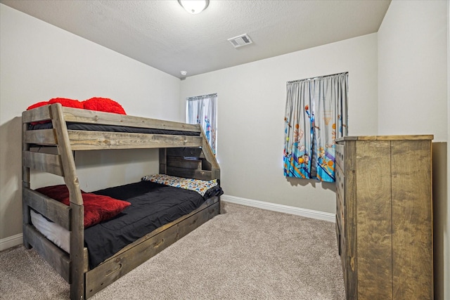 carpeted bedroom with baseboards, visible vents, and a textured ceiling