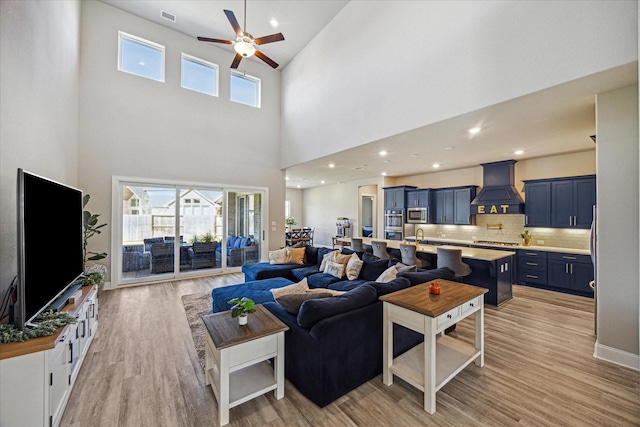 living room featuring light wood finished floors, a ceiling fan, and recessed lighting