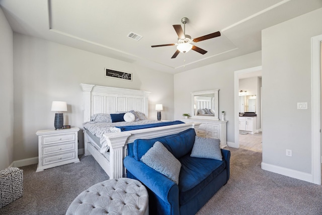 carpeted bedroom with a tray ceiling, a ceiling fan, visible vents, and baseboards