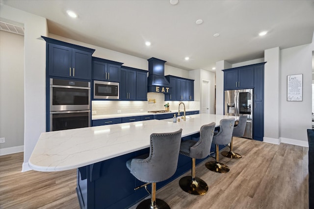 kitchen featuring a large island, a kitchen bar, light stone counters, and stainless steel appliances