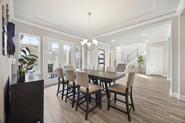 dining room with light wood-style floors, baseboards, stairway, and ornamental molding