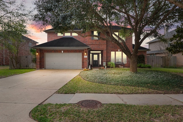 traditional-style home with brick siding, fence, concrete driveway, a lawn, and a garage