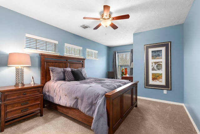 carpeted bedroom with ceiling fan and a textured ceiling