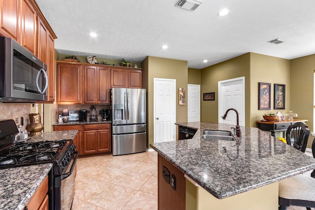 kitchen with stainless steel appliances, a kitchen breakfast bar, a kitchen island with sink, and sink