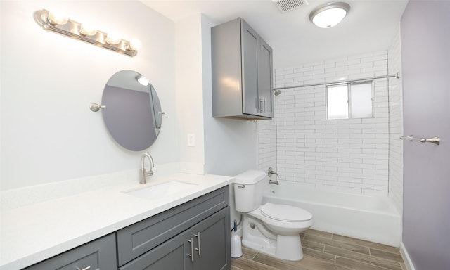 full bathroom with vanity, tiled shower / bath, and toilet