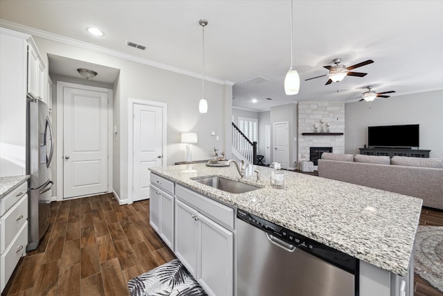 kitchen with sink, appliances with stainless steel finishes, white cabinetry, a kitchen island with sink, and hanging light fixtures