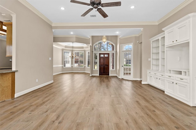 foyer entrance with ceiling fan with notable chandelier, light hardwood / wood-style flooring, ornamental molding, and plenty of natural light