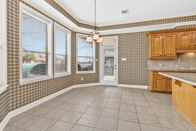 kitchen featuring pendant lighting, backsplash, crown molding, and a chandelier