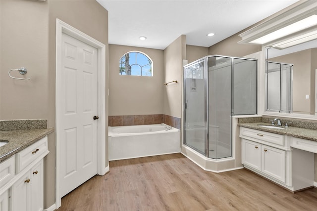 bathroom with hardwood / wood-style flooring, vanity, and plus walk in shower