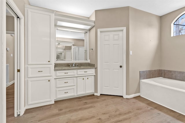 bathroom with a washtub, hardwood / wood-style floors, and vanity