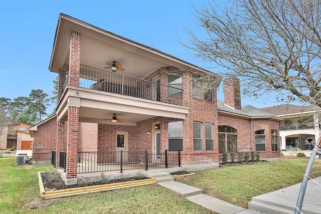 view of front of property with central AC, a balcony, a front yard, and ceiling fan