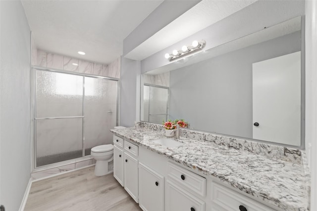 bathroom featuring vanity, an enclosed shower, hardwood / wood-style flooring, and toilet