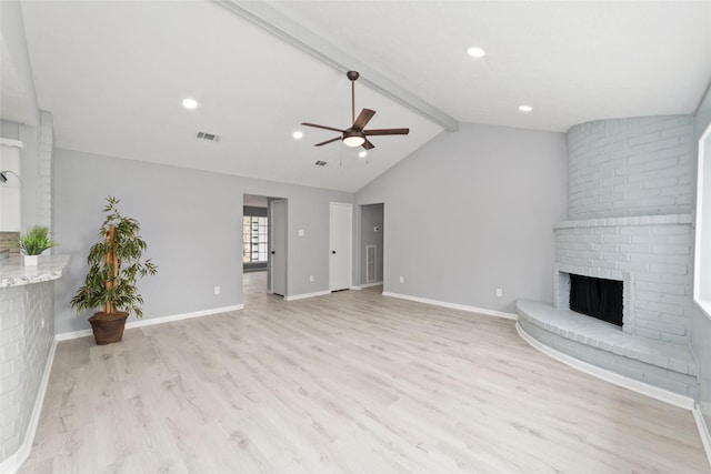 unfurnished living room featuring ceiling fan, light hardwood / wood-style floors, a brick fireplace, and vaulted ceiling with beams