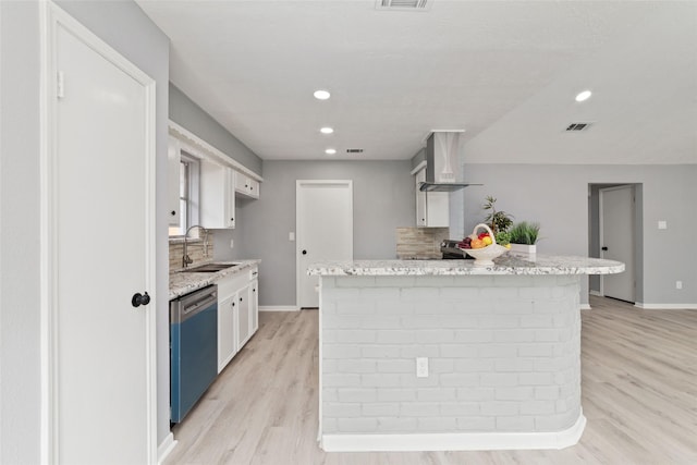 kitchen featuring white cabinets, wall chimney range hood, sink, and dishwasher