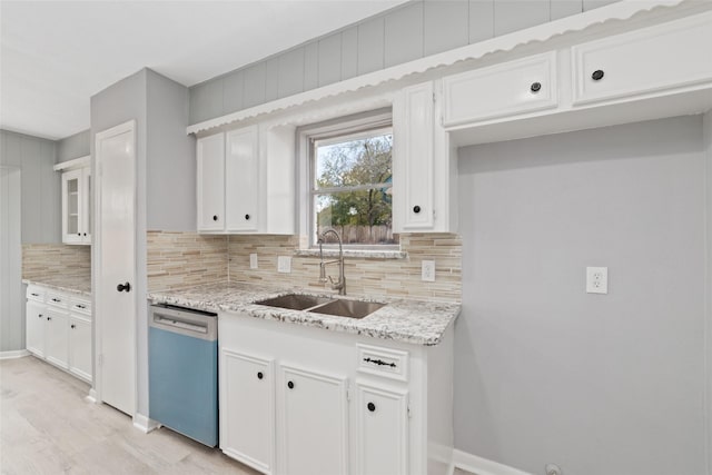 kitchen featuring dishwasher, sink, light stone countertops, and white cabinets