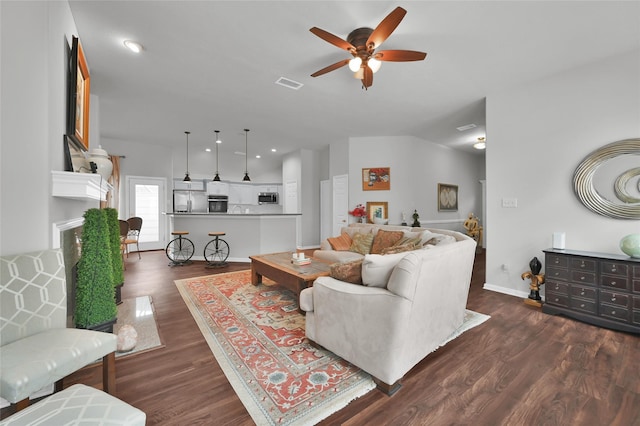 living room with ceiling fan, dark hardwood / wood-style floors, and vaulted ceiling