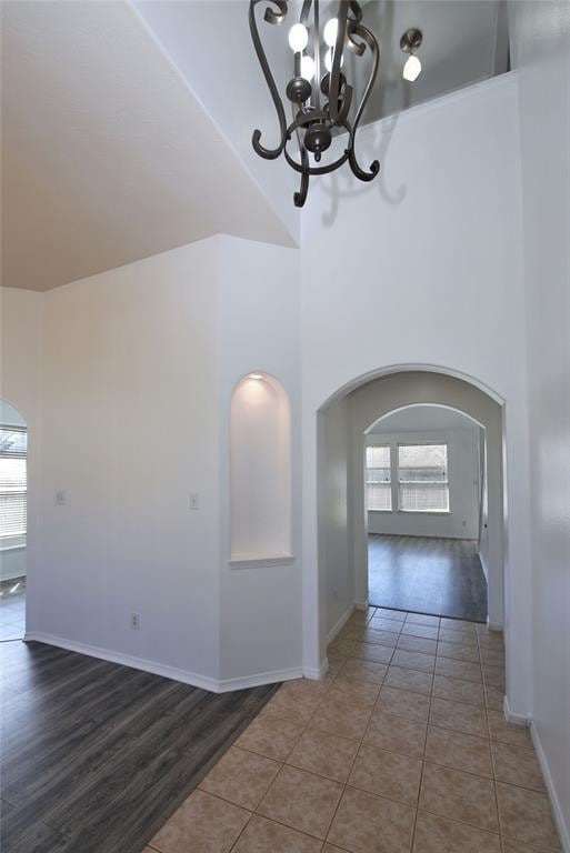 hallway with hardwood / wood-style floors, a notable chandelier, and a towering ceiling