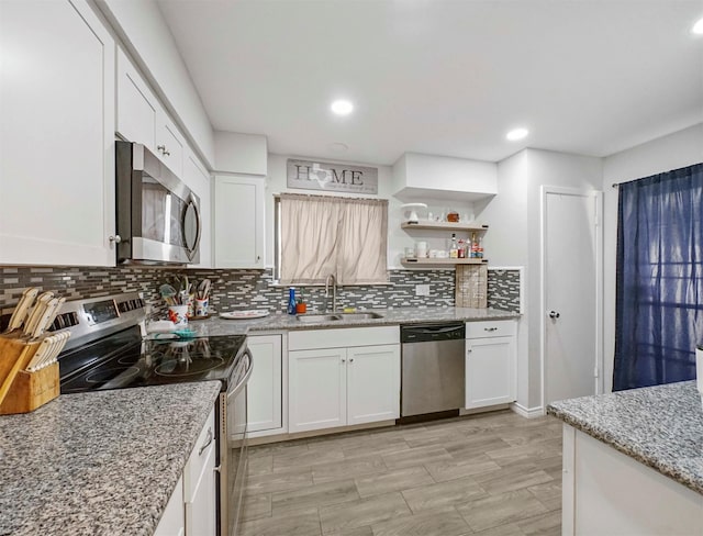 kitchen with stainless steel appliances, white cabinetry, sink, and tasteful backsplash