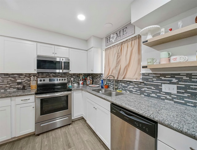 kitchen with sink, light stone counters, tasteful backsplash, appliances with stainless steel finishes, and white cabinets