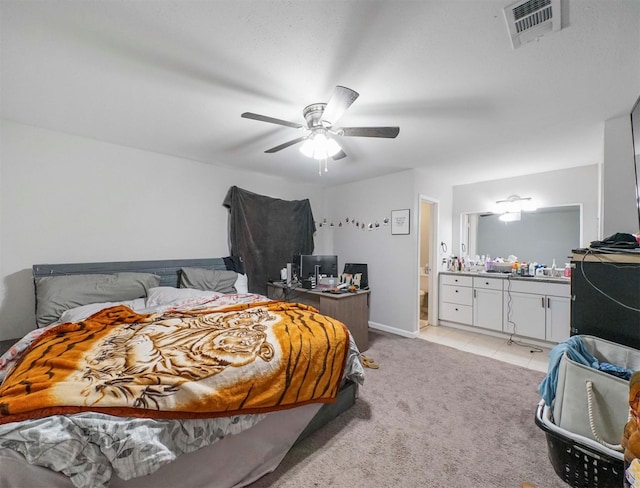 bedroom featuring ensuite bathroom, light colored carpet, and ceiling fan