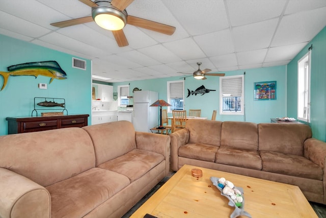 living room featuring a paneled ceiling and ceiling fan