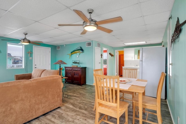 dining space featuring ceiling fan, a paneled ceiling, and wood-type flooring