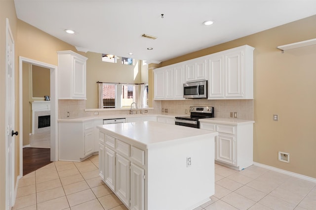 kitchen with appliances with stainless steel finishes, a kitchen island, and white cabinets